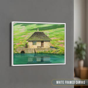 May include: A white framed canvas print of a painting depicting a small, stone cottage with a green roof, nestled in a lush green field with wildflowers. The cottage has a wooden door and windows, and there is a small pond in front of it. The sky is a light blue.