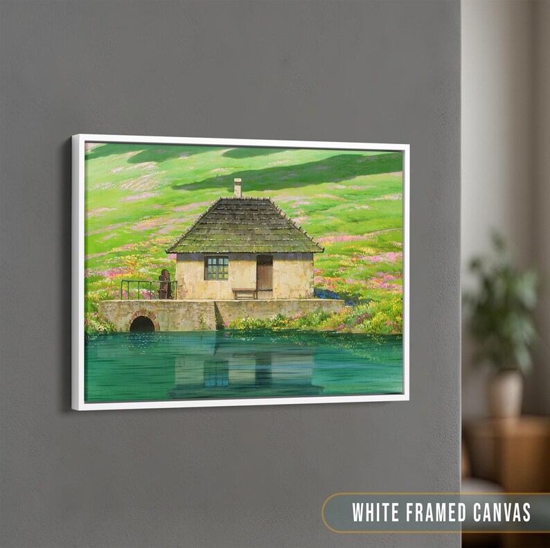 May include: A white framed canvas print of a painting depicting a small, stone cottage with a green roof, nestled in a lush green field with wildflowers. The cottage has a wooden door and windows, and there is a small pond in front of it. The sky is a light blue.
