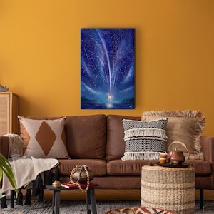 May include: A painting of a starry night sky with shooting stars and a glowing light in the distance. The painting is framed and hanging on a yellow wall above a brown leather couch.