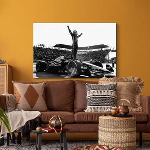 May include: Black and white canvas print of a Formula 1 race car with a driver standing on top, arms raised in victory. The car has the Oracle and Mobil logos. The background shows a packed stadium.