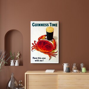 May include: A vintage Guinness advert featuring a red crab holding a glass of Guinness with the text "GUINNESS TIME" and "Have this one with me!"