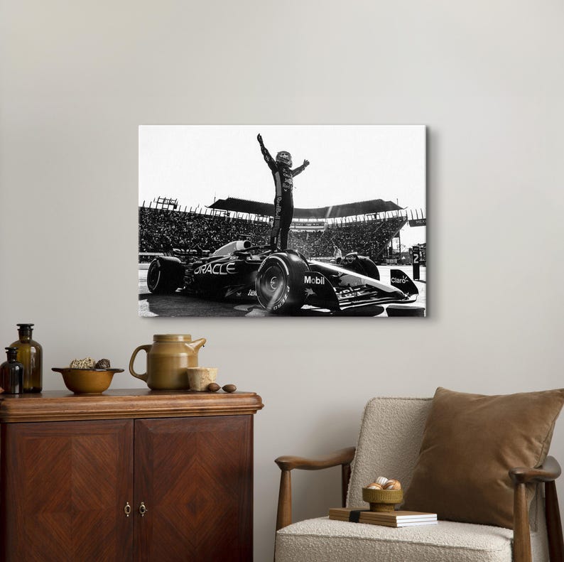 May include: Black and white canvas print of a Formula 1 race car with a driver standing on top, arms raised in victory. The car has sponsor logos, and a crowd fills the background.