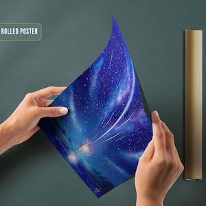 May include: A canvas rolled poster featuring a blue and purple night sky with a bright white shooting star and a glowing light in the distance. The poster is rolled up and held by a hand.