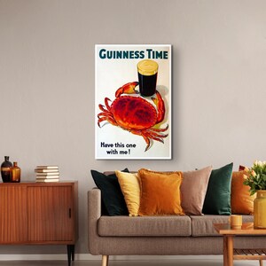 May include: A vintage Guinness beer advert featuring a red crab holding a glass of Guinness with the text "GUINNESS TIME" and "Have this one with me!"