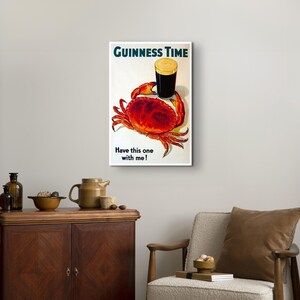 May include: A vintage Guinness beer advert featuring a glass of Guinness and a red crab with the text "GUINNESS TIME" and "Have this one with me!"