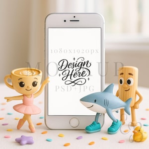 May include: A white smartphone mockup with the text "Design Here" on the screen, surrounded by whimsical figurines. A coffee cup ballerina, a shark in sneakers, and a wooden figure are arranged around the phone. Colorful confetti dots the surface.