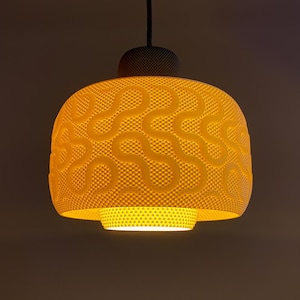 May include: A yellow pendant light with a textured lampshade featuring a pattern of curved lines. The lampshade is rounded and suspended from a black cord. The top of the light fitting is dark grey.