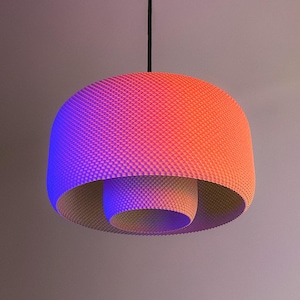 May include: A contemporary pendant light with a textured, domed lampshade. The shade has a colour gradient, transitioning from blue to orange. The inner cylinder is a lighter shade. It hangs from a black cord.