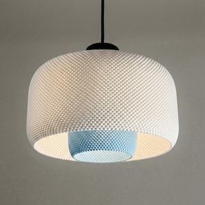 Könnte beinhalten: Eine moderne Pendelleuchte mit einem strukturierten weißen Schirm und einem blauen Innenraum. Das Licht hängt an einem schwarzen Kabel und Baldachin. Der Schirm hat ein geometrisches Muster.