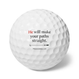 May include: White golf ball with a dimpled surface. The ball features the text "He will make your paths straight." in black and red, along with "PROVERBS 3:6". A golf-themed gift.