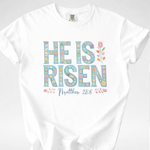Camiseta con cruz de Pascua floral – Camiseta cristiana "Él ha resucitado"