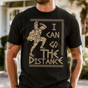 A man wearing a black t-shirt with a graphic design printed on it, standing in front of a house.
