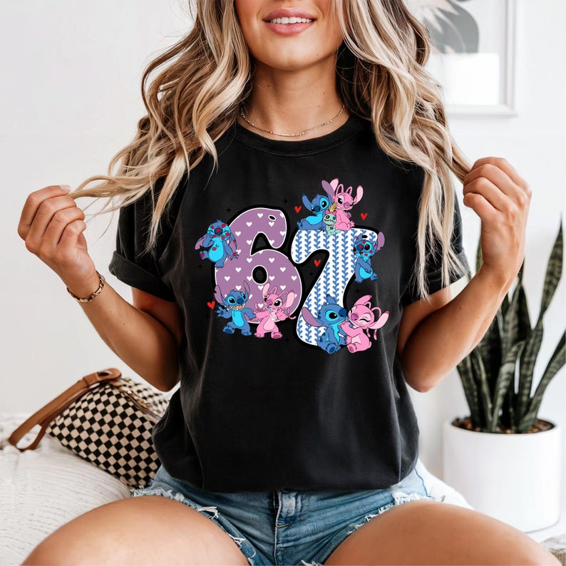 A woman wearing a black t-shirt with a graphic design featuring the number 61 and various cartoon characters.