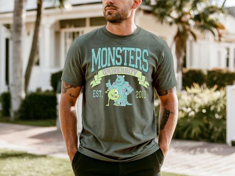 A man wearing a green t-shirt with a graphic design of a character from the Monsters University animated series.