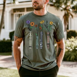 A man wearing a green t-shirt with a graphic design of colorful flowers and vases.