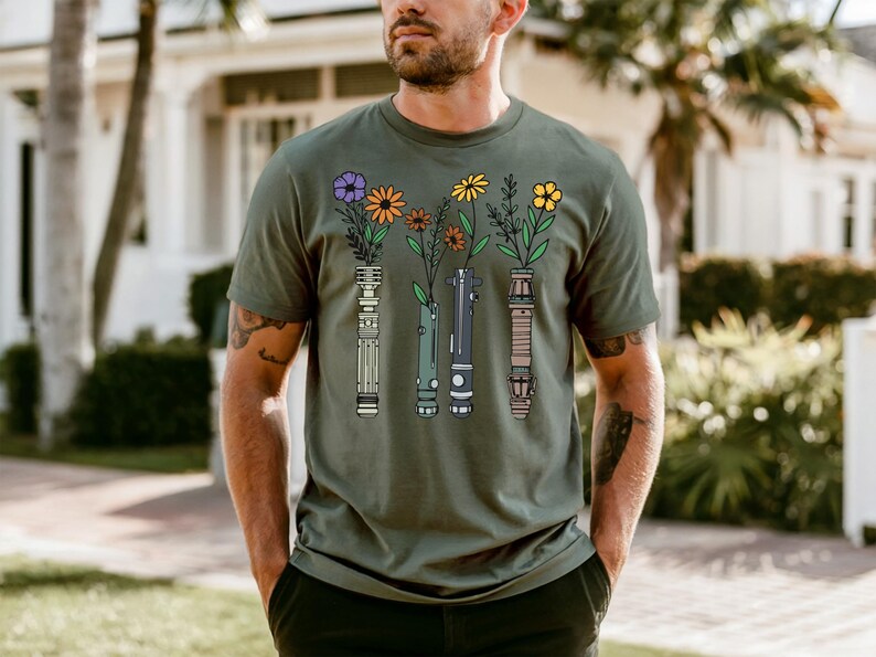 A man wearing a green t-shirt with a graphic design of colorful flowers and vases.
