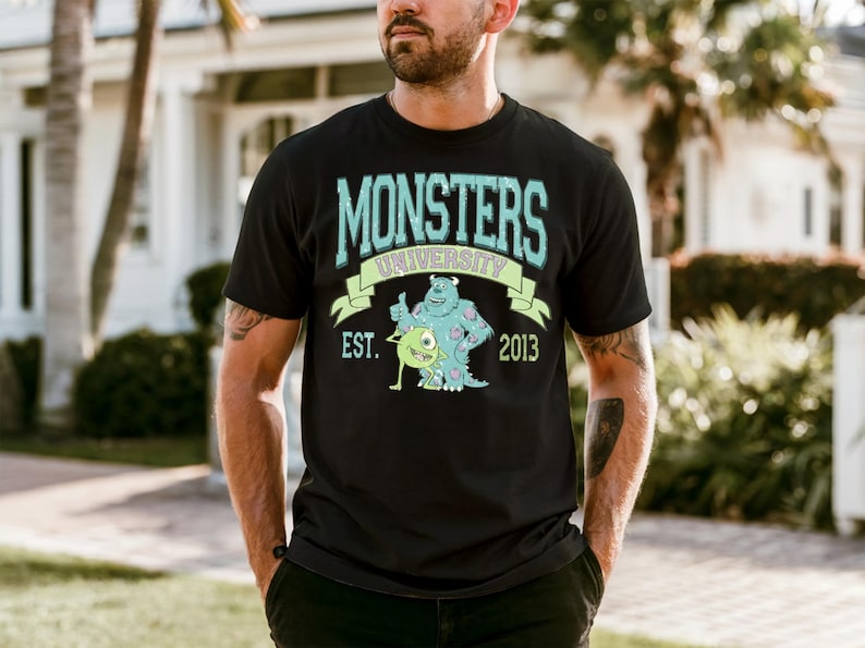 A man wearing a black t-shirt with a graphic design featuring a character from the animated movie Monsters University.