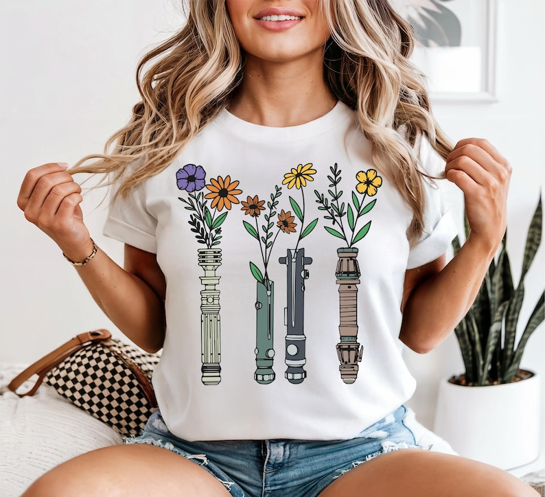 A woman wearing a white t-shirt with a graphic design of four vases with flowers and plants.