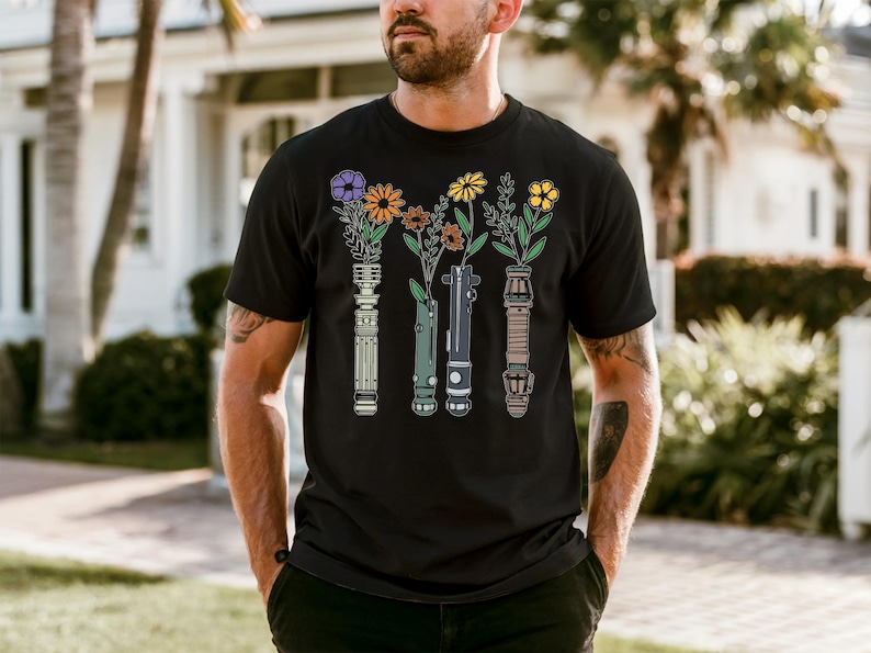 A man wearing a black t-shirt with a graphic design of colorful flowers and vases.