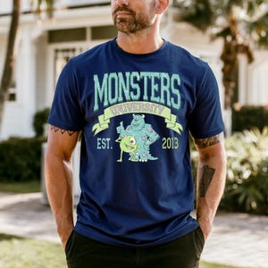 A man wearing a blue t-shirt with a graphic design of a character from the animated movie Monsters University.