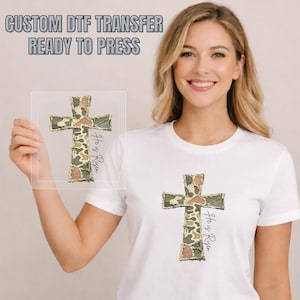 May include: A white t-shirt featuring a camouflage cross design with the text "He is Risen" in a handwritten font. The image also shows a clear DTF transfer with the same cross design and the text "Custom DTF Transfer Ready to Press".