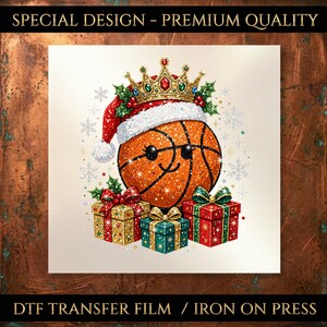 Könnte beinhalten: Eine DTF-Transferfolie mit einem lächelnden Basketball, der eine rote Weihnachtsmütze und eine goldene Krone mit Edelsteinen trägt. Der Basketball ist von drei Geschenkpaketen in Gold, Türkis und Rot sowie Stechpalmen und Schneeflocken umgeben.