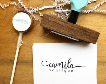 May include: A wooden stamp with a light blue handle and the text "camilla boutique" printed on a white card.