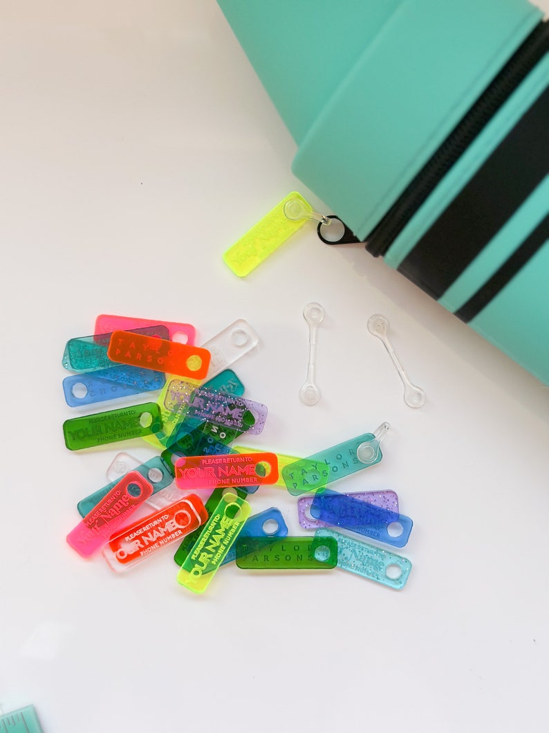 May include: Assortment of colorful plastic name tags with glitter and text that reads "Please return to [Your Name] Phone Number".