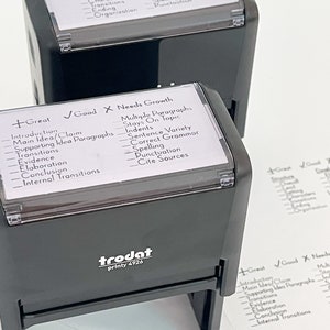 May include: Two black rubber stamps with clear plastic tops. The stamps are used for grading student work. The top stamp has the categories "Great", "Good", and "Needs Work". The bottom stamp has the categories "Great", "Good", and "Needs Growth".