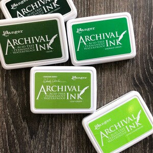 Peut inclure: Cinq tampons d'encre dans diff&eacute;rentes nuances de vert. Chaque tampon est &eacute;tiquet&eacute; "Ranger Archival Ink" et comprend le nom de la couleur : Vert Biblioth&egrave;que, Olive, Vert &Eacute;meraude, Vert Feuille et Chartreuse Vif.