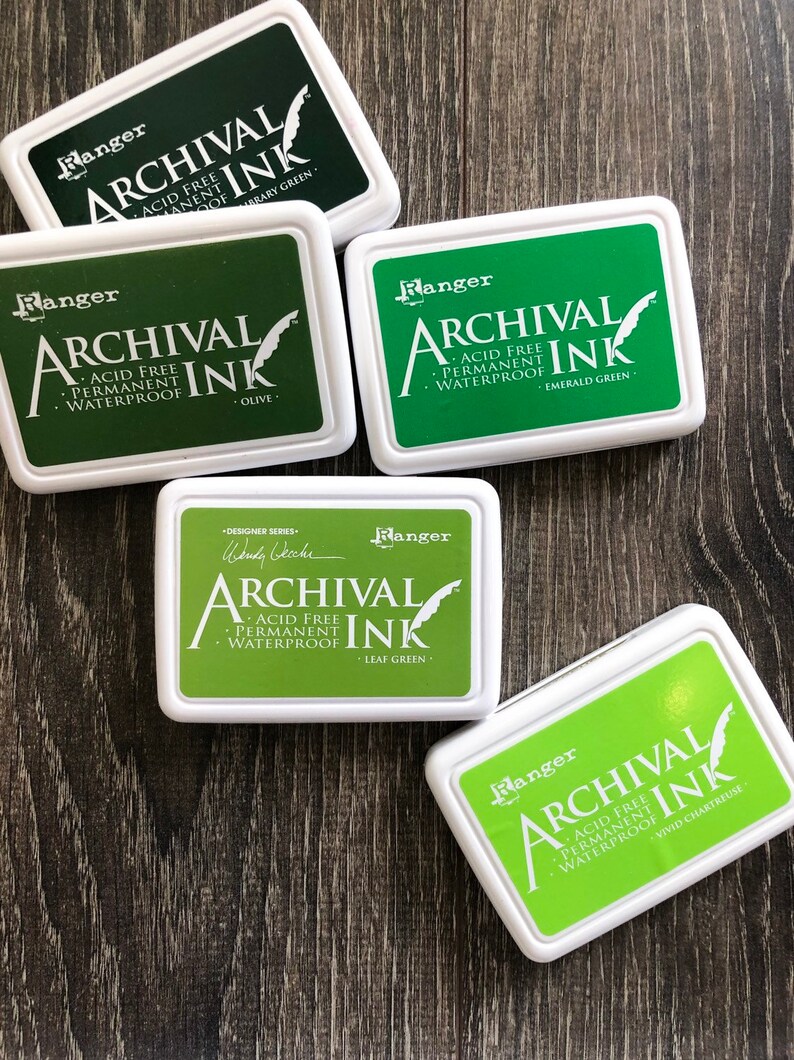 Peut inclure: Cinq tampons d'encre dans diff&eacute;rentes nuances de vert. Chaque tampon est &eacute;tiquet&eacute; "Ranger Archival Ink" et comprend le nom de la couleur : Vert Biblioth&egrave;que, Olive, Vert &Eacute;meraude, Vert Feuille et Chartreuse Vif.