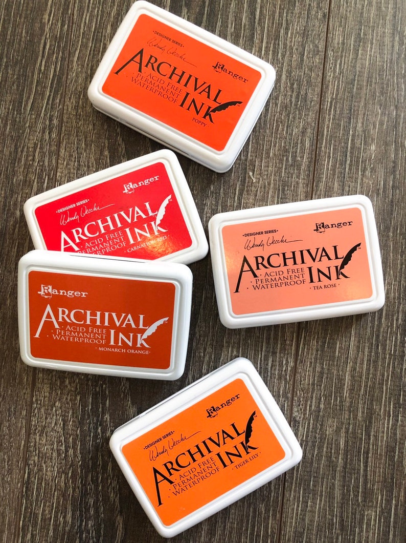 Peut inclure: Cinq tampons d'encre dans diff&eacute;rentes nuances d'orange et de rose. Chaque tampon est &eacute;tiquet&eacute; "Ranger Archival Ink" avec le nom de la couleur et "Sans acide, permanent, imperm&eacute;able".