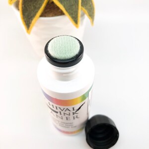 May include: A white bottle with a black cap and a green sponge applicator. The bottle is labeled "Chival Ink Cleaner".