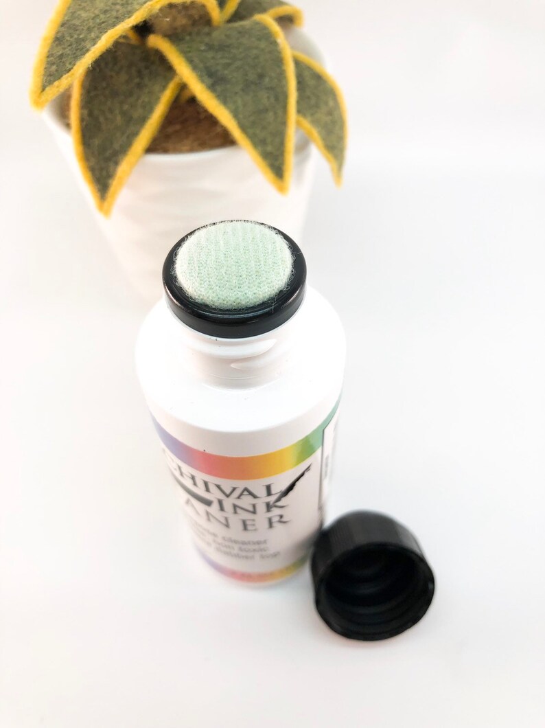 May include: A white bottle with a black cap and a green sponge applicator. The bottle is labeled "Chival Ink Cleaner".