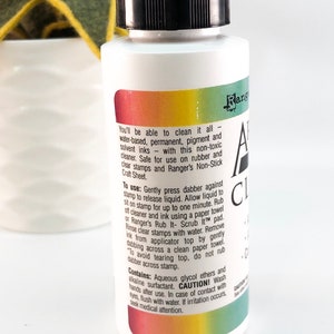 May include: A clear plastic bottle with a black cap and a rainbow label. The label reads "Ranger All Clear Cleaner" and includes instructions for use and cautions.