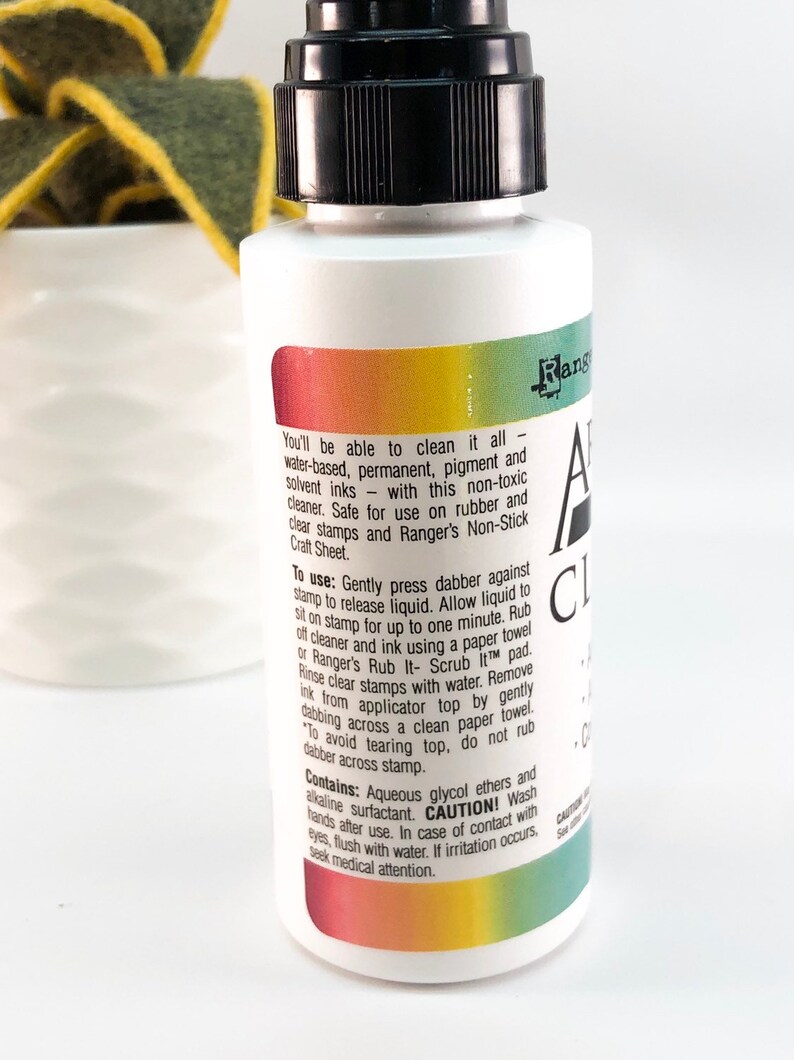 May include: A clear plastic bottle with a black cap and a rainbow label. The label reads "Ranger All Clear Cleaner" and includes instructions for use and cautions.