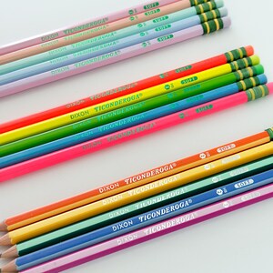 May include: A collection of colorful Dixon Ticonderoga pencils. The pencils are arranged in rows, showcasing a variety of vibrant colors including pink, orange, yellow, green, blue, and purple. Each pencil has the brand name printed on it and a green eraser.