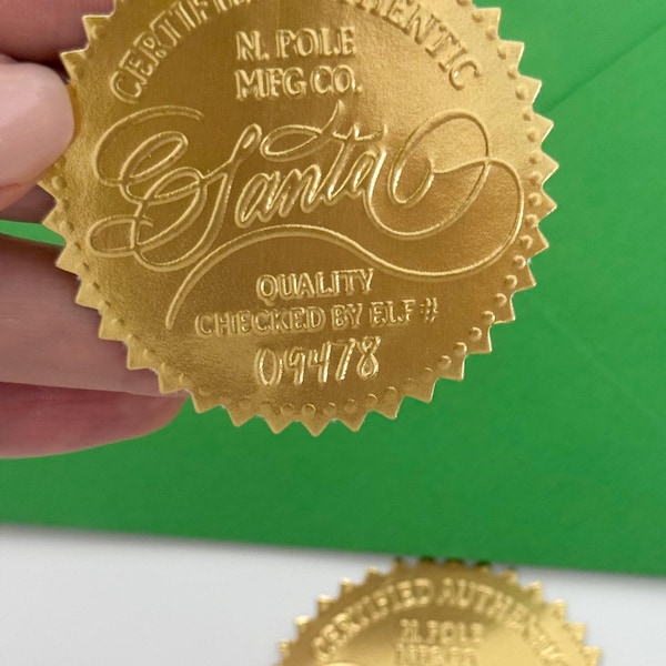Puede incluir: Sello de lámina dorada con las palabras "CERTIFIED AUTHENTIC" y "SANTA" en escritura elegante. El sello también incluye el texto "N. POLE MFG CO." y "QUALITY CHECKED BY ELF # 09478". El sello tiene un borde festoneado.