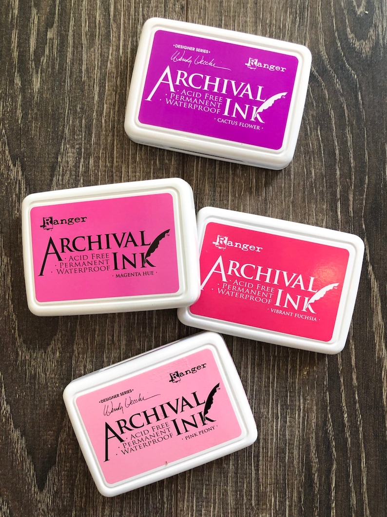Peut inclure: Quatre tampons d'encre dans des contenants blancs avec des lettres noires. Les tampons d'encre sont &eacute;tiquet&eacute;s "Ranger Archival Ink" et chacun a une encre de couleur diff&eacute;rente : fleur de cactus, teinte magenta, fuchsia vibrant et pivoine rose.