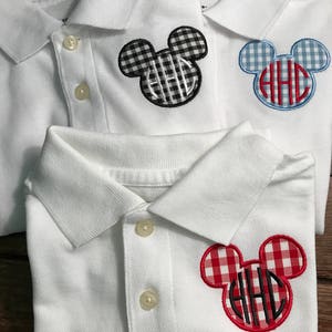 May include: White polo shirts with Mickey Mouse-shaped patches. The patches feature a monogram with the letters "HHC" in black, and are in black and white gingham, blue and white gingham, and red and white gingham patterns.