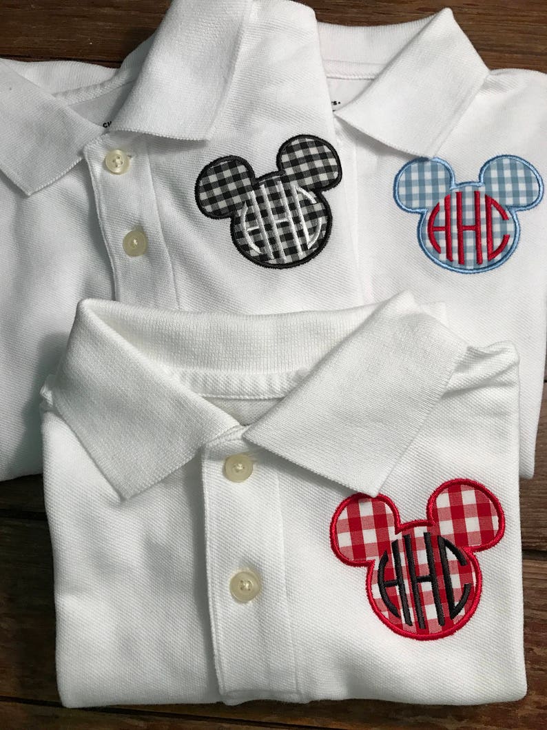 May include: White polo shirts with Mickey Mouse-shaped patches. The patches feature a monogram with the letters "HHC" in black, and are in black and white gingham, blue and white gingham, and red and white gingham patterns.
