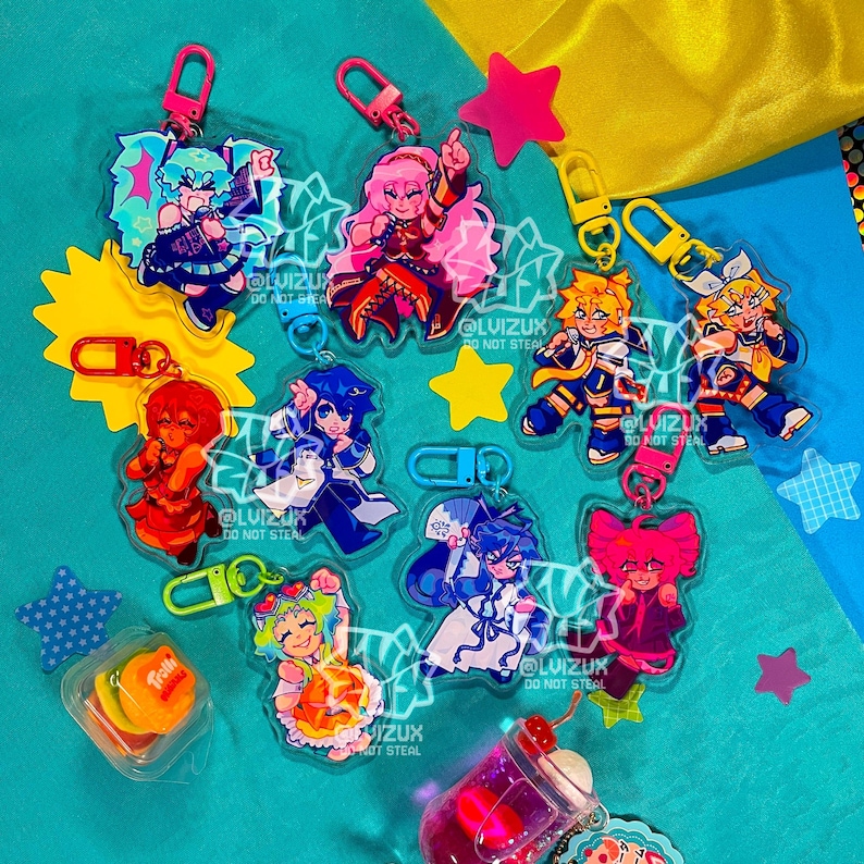 May include: A set of nine colorful anime character keychains with clear plastic backgrounds. Each keychain features a different character with a unique pose and expression. The keychains are attached to silver metal rings.