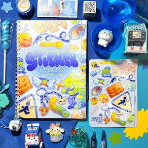 May include: A collection of colorful stickers, a spiral notebook, and various small toys arranged on a blue surface. The notebook features the text "Sticker Heaven" in a bubble font. Other items include a blue lollipop, a small arcade game, and a milk carton.
