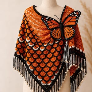 May include: A crochet poncho in vibrant orange, featuring a black and white scalloped pattern, a large three-dimensional orange and black butterfly appliqué, and a bottom hem finished with long black and white fringe accented by small white beads.