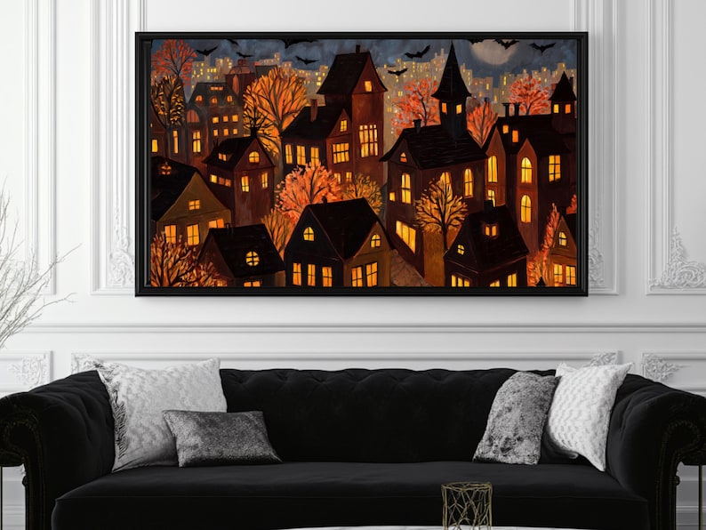 May include: A framed art print depicts a nighttime cityscape with illuminated houses and autumn trees. The artwork features a dark color palette with warm orange and yellow lights, bats, and a full moon, creating a spooky Halloween theme.