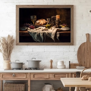 May include: A framed still life painting depicts a rustic table setting. A loaf of bread, grapes, and a glass of wine are arranged on a draped cloth. A lit candle and olive oil bottle add to the ambiance. The painting is set against a white brick wall.