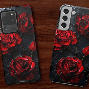 Pu&ograve; includere: Una custodia per telefono nera con sfondo scuro e rose rosse. La custodia ha un ritaglio per la fotocamera e un bordo argentato.