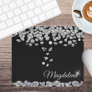 May include: Black mouse pad with a design of silver diamonds cascading down from the top. The name "Magdalena" is written in white at the bottom of the mouse pad.