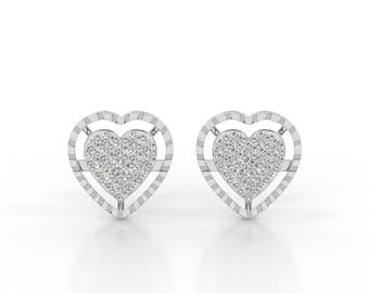 May include: A pair of silver-toned heart-shaped stud earrings. Each earring features a central heart section encrusted with small, clear, sparkling stones, surrounded by an outer heart-shaped frame with a textured, ribbed metallic border.
