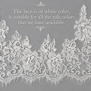 May include: A white lace trim featuring an intricate floral pattern with scalloped edges. The text on the image reads: The lace is of white colour, is suitable for all the tule colours that we have available. The lace has a delicate, openwork design.